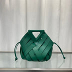 Green  leather handbag on a reflective surface with a neutral background