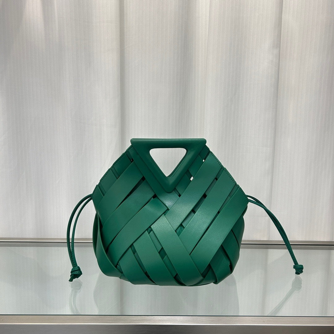 Green  leather handbag on a reflective surface with a neutral background