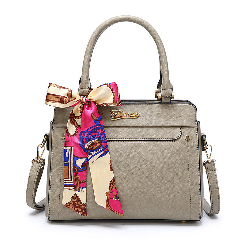 Beige handbag with a colorful scarf attached on a white background
