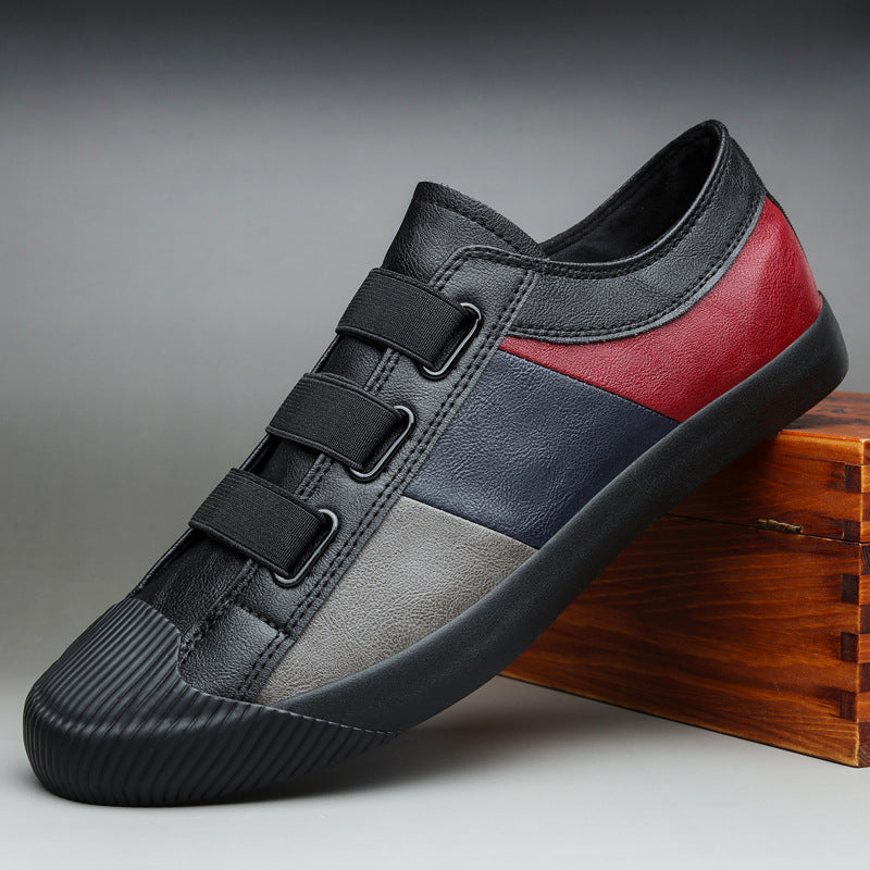 Black, gray, and red sneaker with velcro straps on a wooden block against a gray background