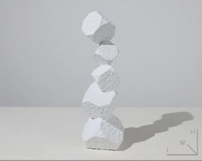 Stack of white stone sculptures on a light gray background