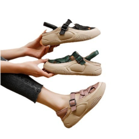 Beige sandals with green straps held by a person on a white background