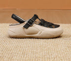 Beige sandal with black straps on a textured beige surface