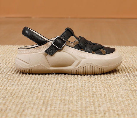 Beige sandal with black straps on a textured beige surface