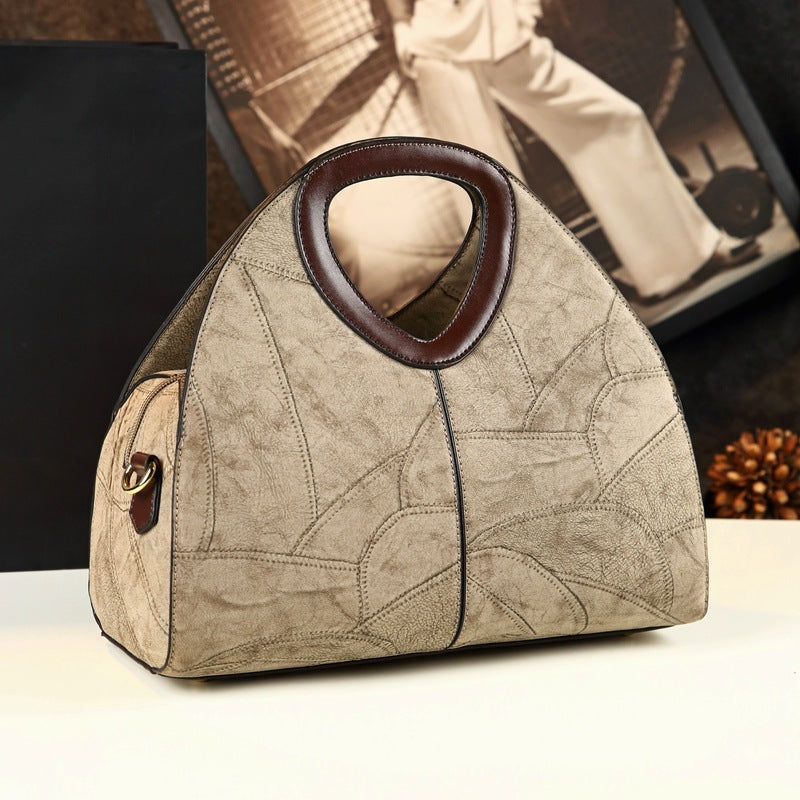 Beige handbag with brown handle on a white surface, blurred background