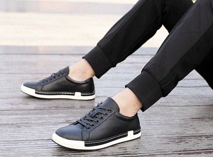 Person wearing black sneakers with white soles on a wooden floor.