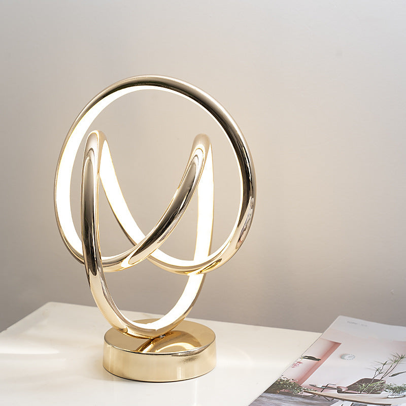 Modern gold table lamp with circular design on a white surface.
