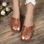 Brown sandals worn on feet with white flowers on a wooden surface
