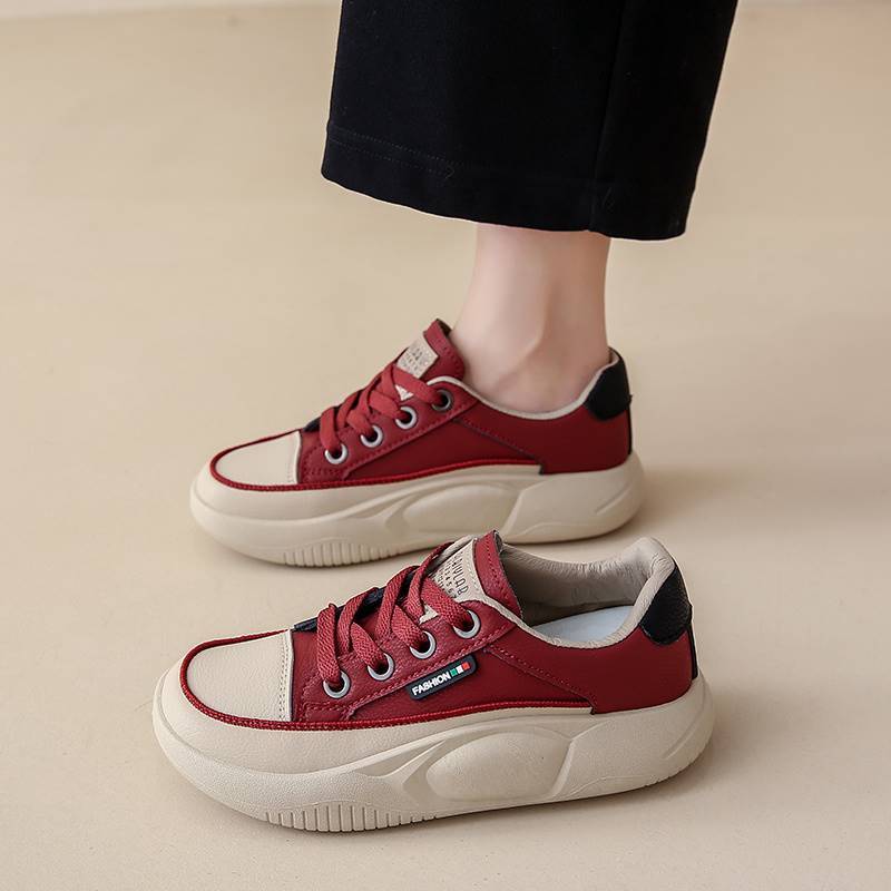 Red sneakers with white soles worn by a person on a beige background