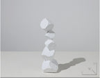 Stack of white stone-like sculptures on a light gray background