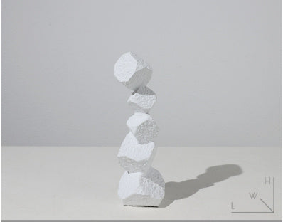 Stack of white stone-like sculptures on a light gray background