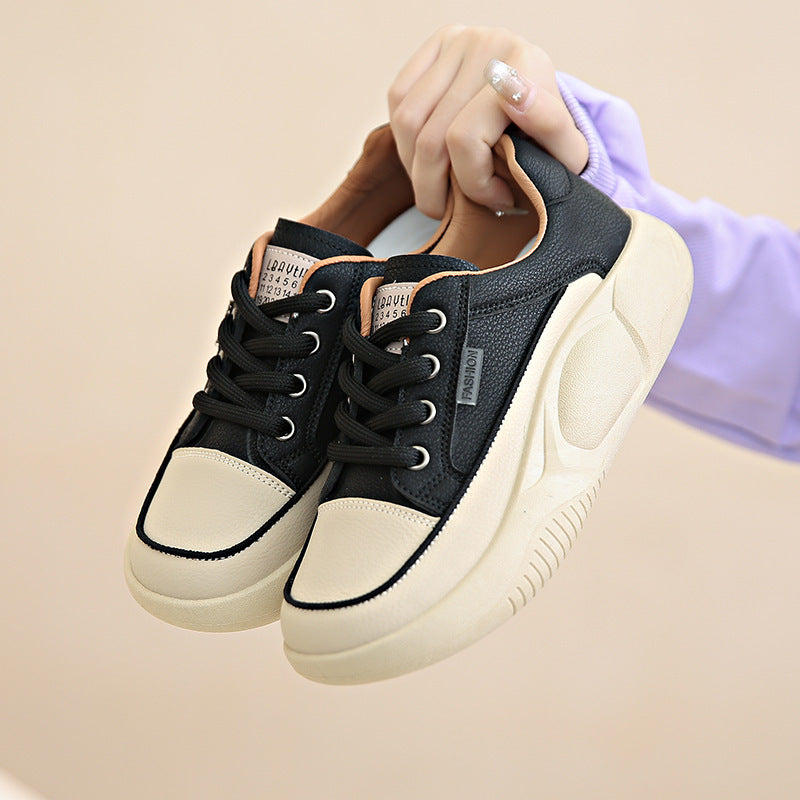Black and beige sneakers held by a hand on a beige background