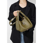 Person holding a green handbag against a plain background