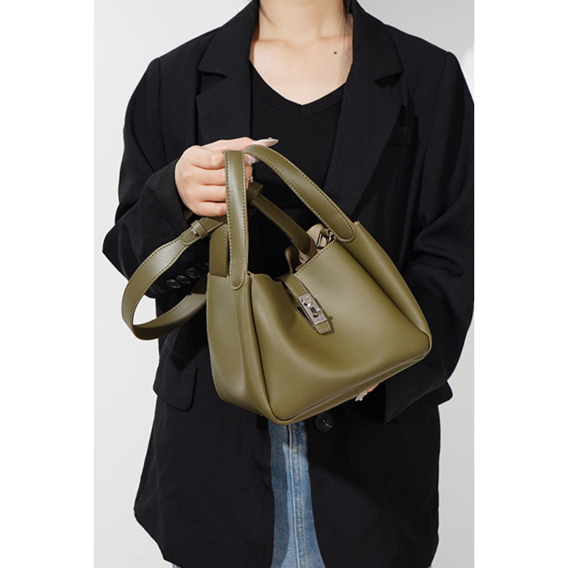 Person holding a green handbag against a plain background