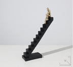 Statue of a thinker on a black staircase against a white background