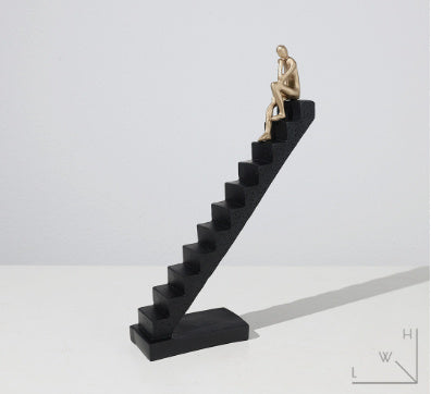 Statue of a thinker on a black staircase against a white background