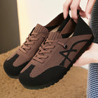 Brown and black sneakers held by a person with a blurred background