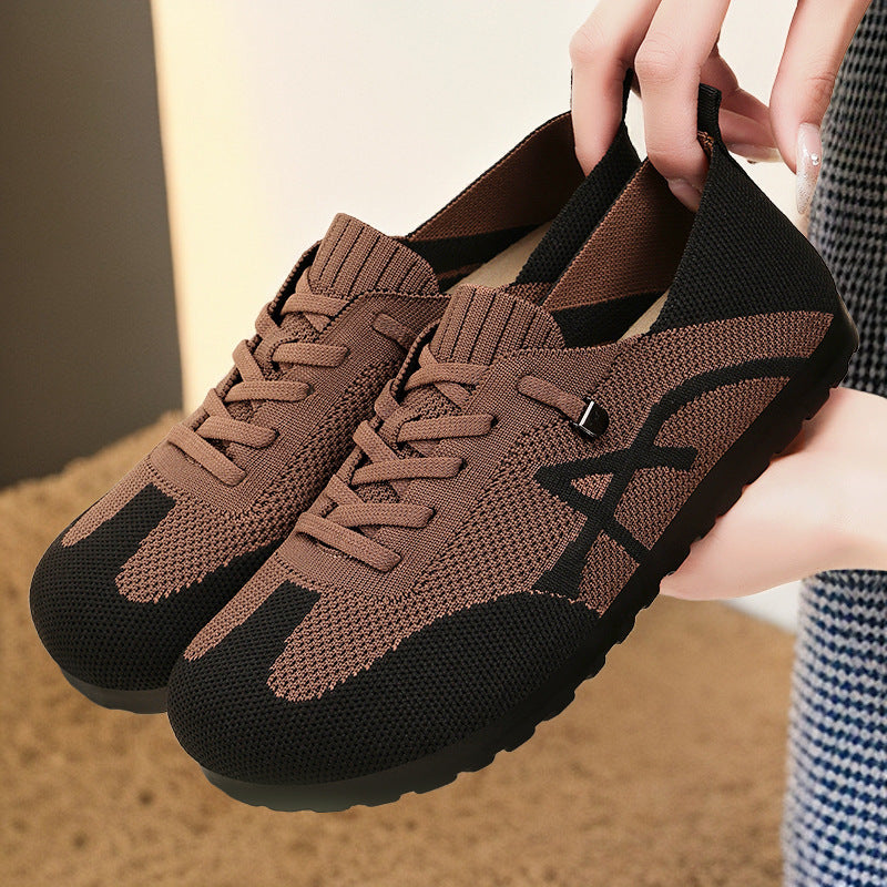 Brown and black sneakers held by a person with a blurred background