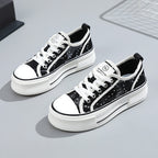 Black and white sneakers with sequin details on a gray surface