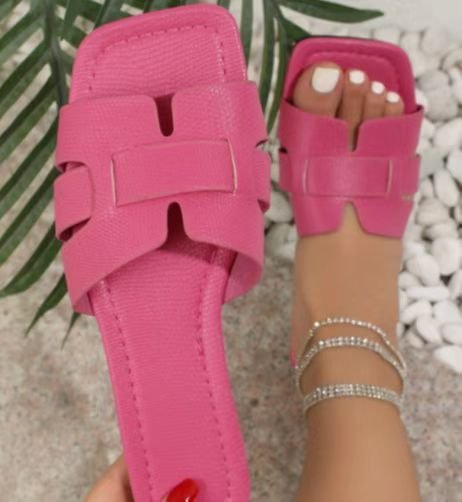 Pink sandals worn on a foot with a blurred background