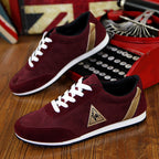 Maroon sneakers with white laces and gold accents on a wooden surface.