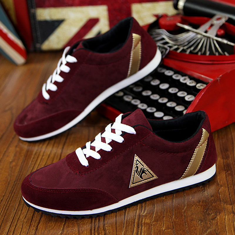Maroon sneakers with white laces and gold accents on a wooden surface.
