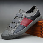 Gray and black sneaker with red accent on a wooden block against a gray background