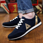 Navy blue sneakers with a gold triangle logo on a wooden floor.