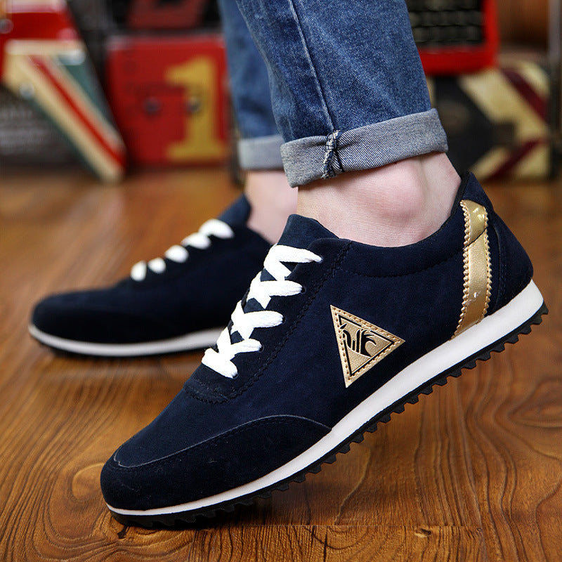 Navy blue sneakers with a gold triangle logo on a wooden floor.