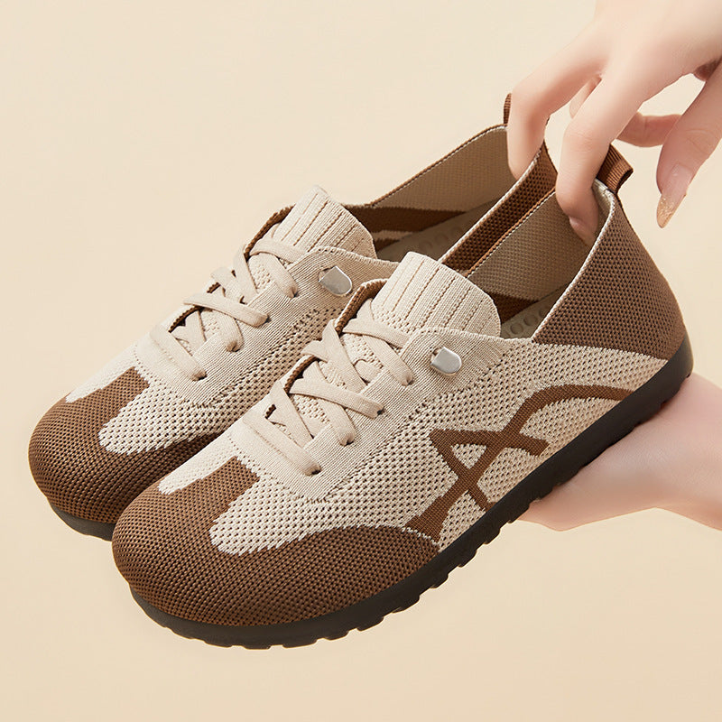 Beige and brown sneakers with a hand holding one shoe on a beige background