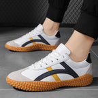 White sneakers with black and yellow accents on a gray floor.