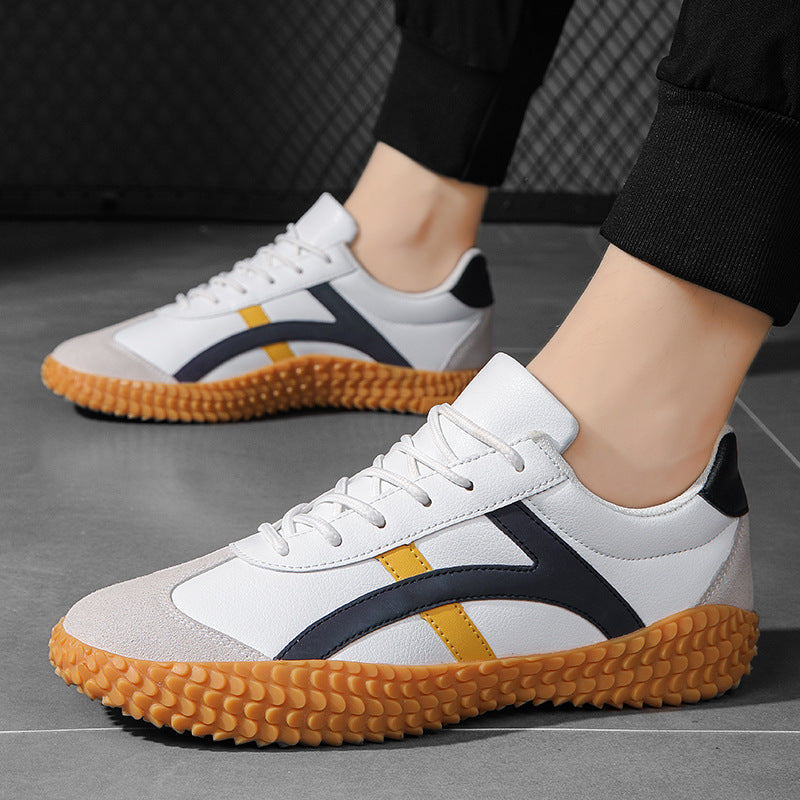White sneakers with black and yellow accents on a gray floor.