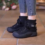 Black high-top sneakers worn with rolled-up jeans on a tiled floor.