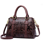 Brown leather handbag with floral patterns on a white background