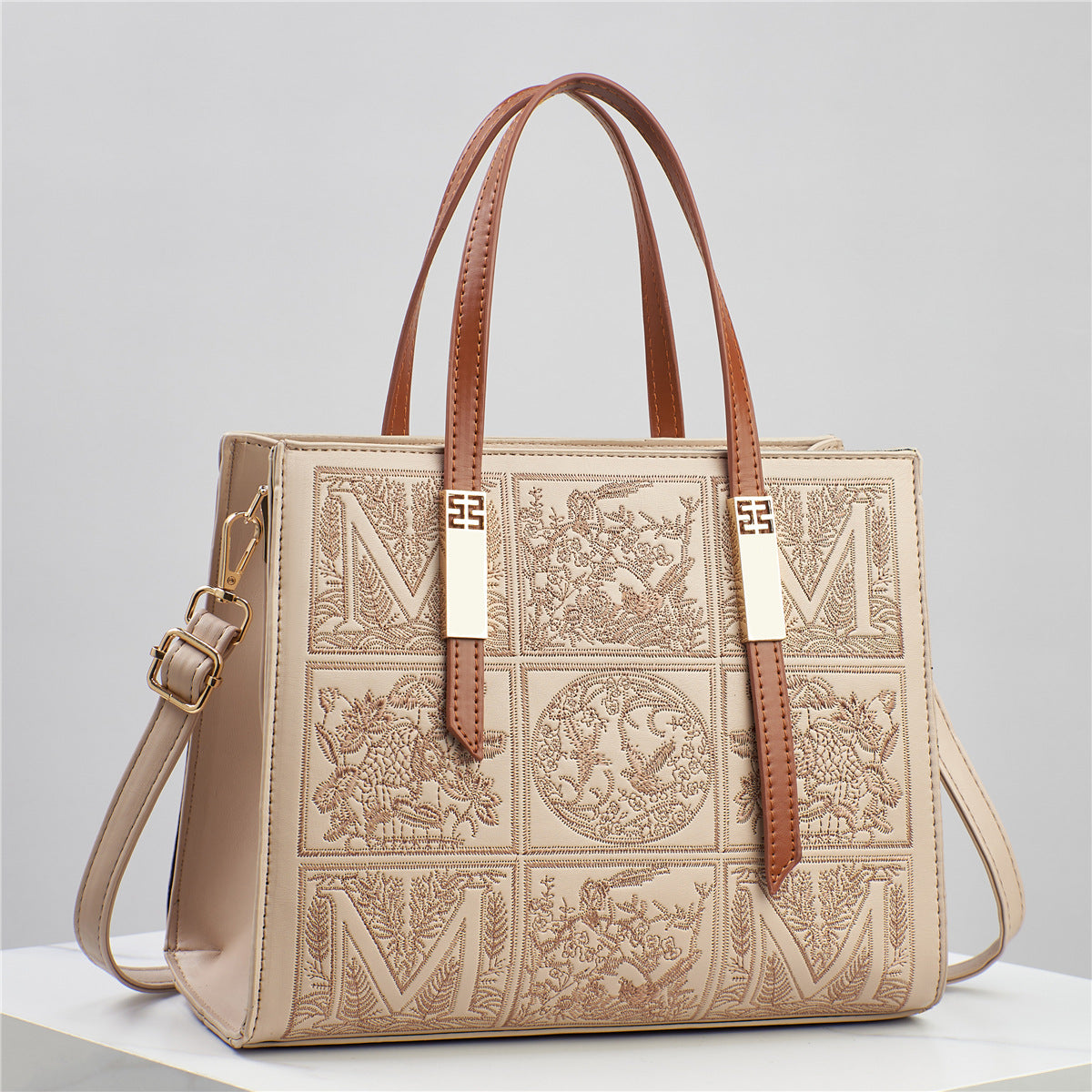Designer handbag with intricate patterns and gold accents on a light gray background