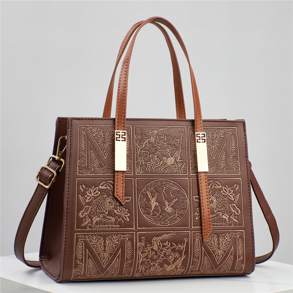 Brown leather handbag with embossed designs on a light gray background