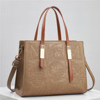 Brown leather handbag with embossed patterns on a light gray background