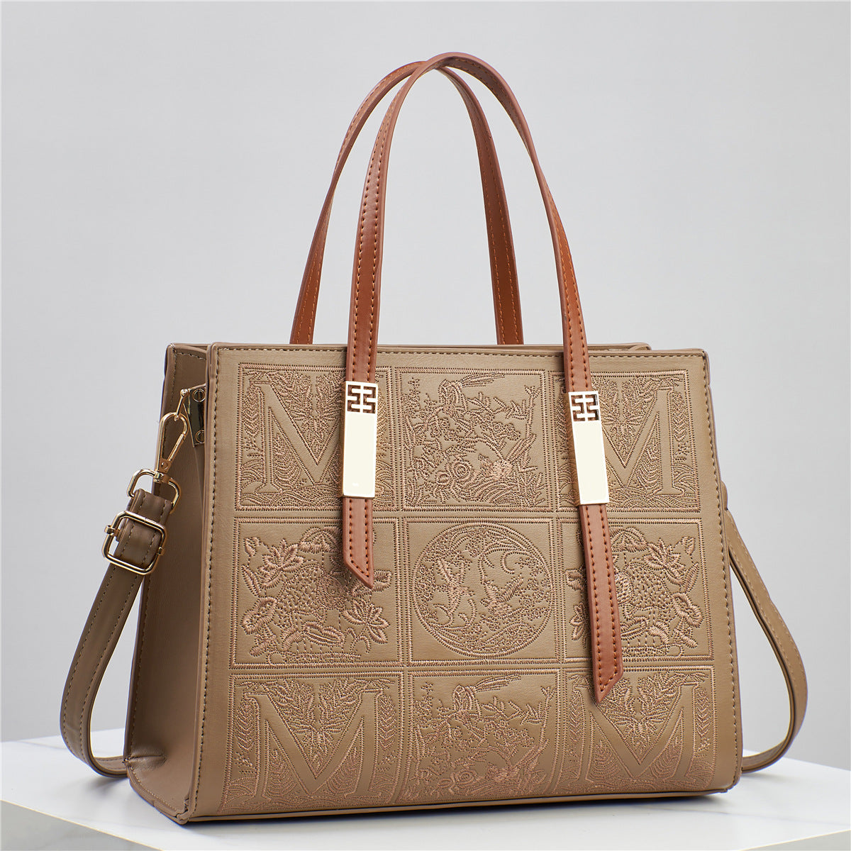 Brown leather handbag with embossed patterns on a light gray background