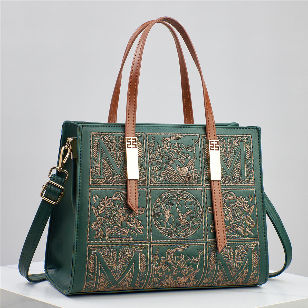 Green handbag with brown leather straps on a light gray background