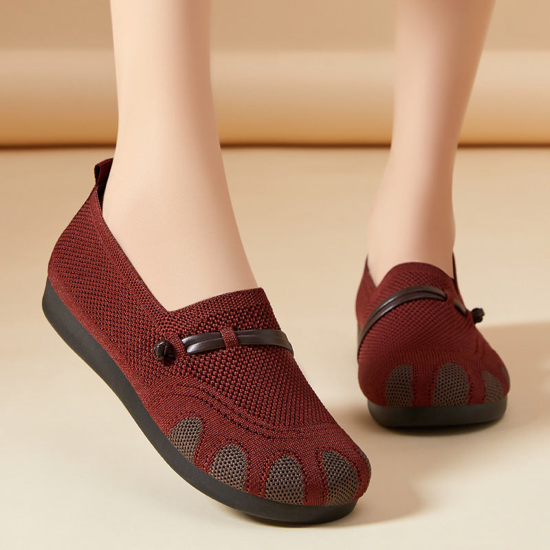 Red slip-on shoes with black soles on a beige background