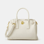 White handbag with gold accents on a light gray background