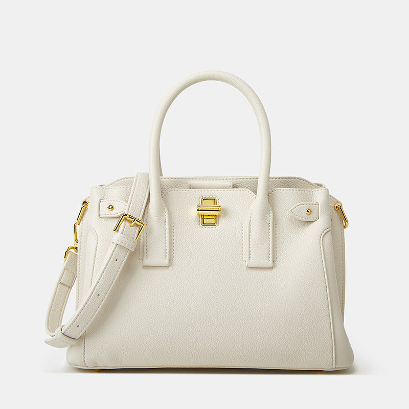 White handbag with gold accents on a light gray background
