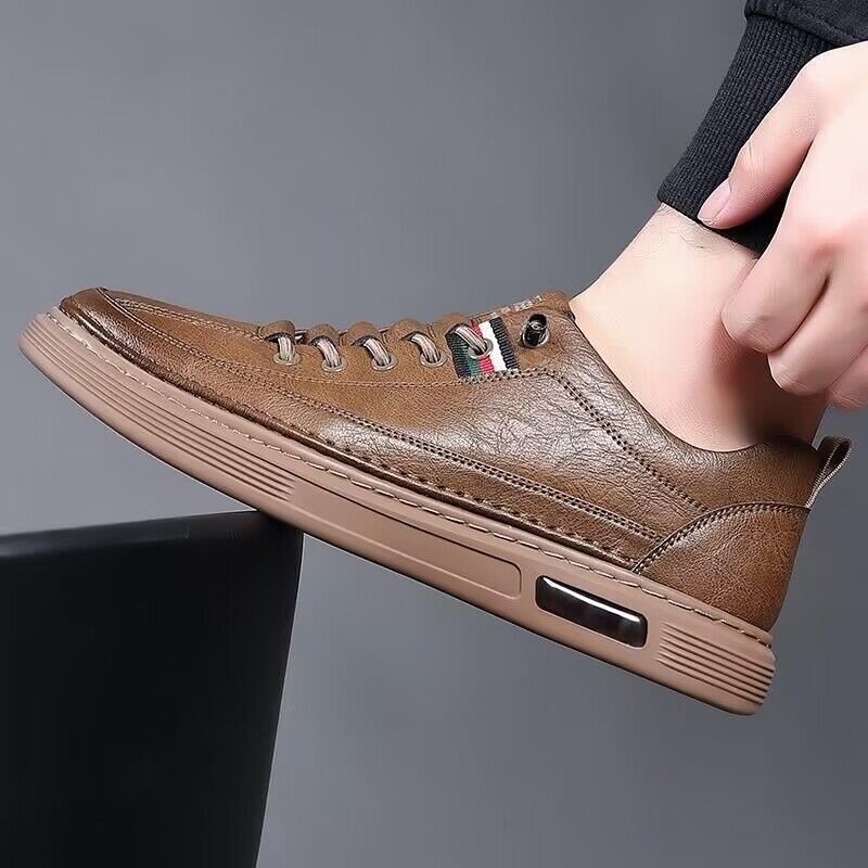 Brown leather sneaker being worn on a gray background