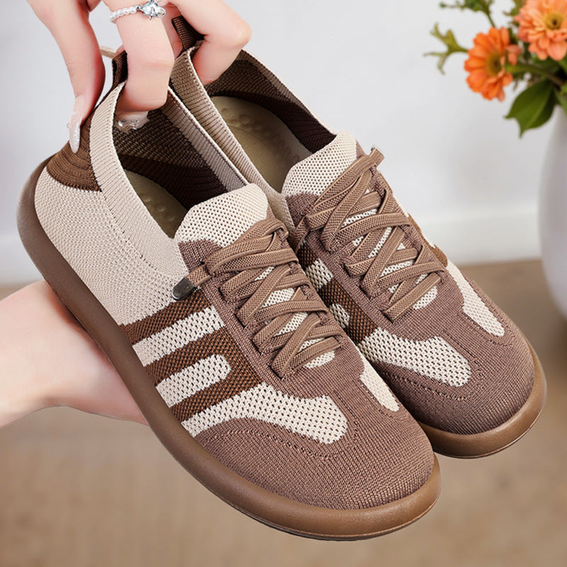 Brown and beige sneakers held by a hand with a blurred background