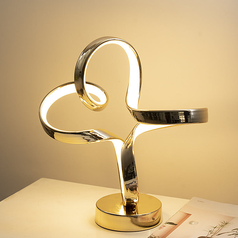 Gold spiral table lamp on a white surface with a soft beige background