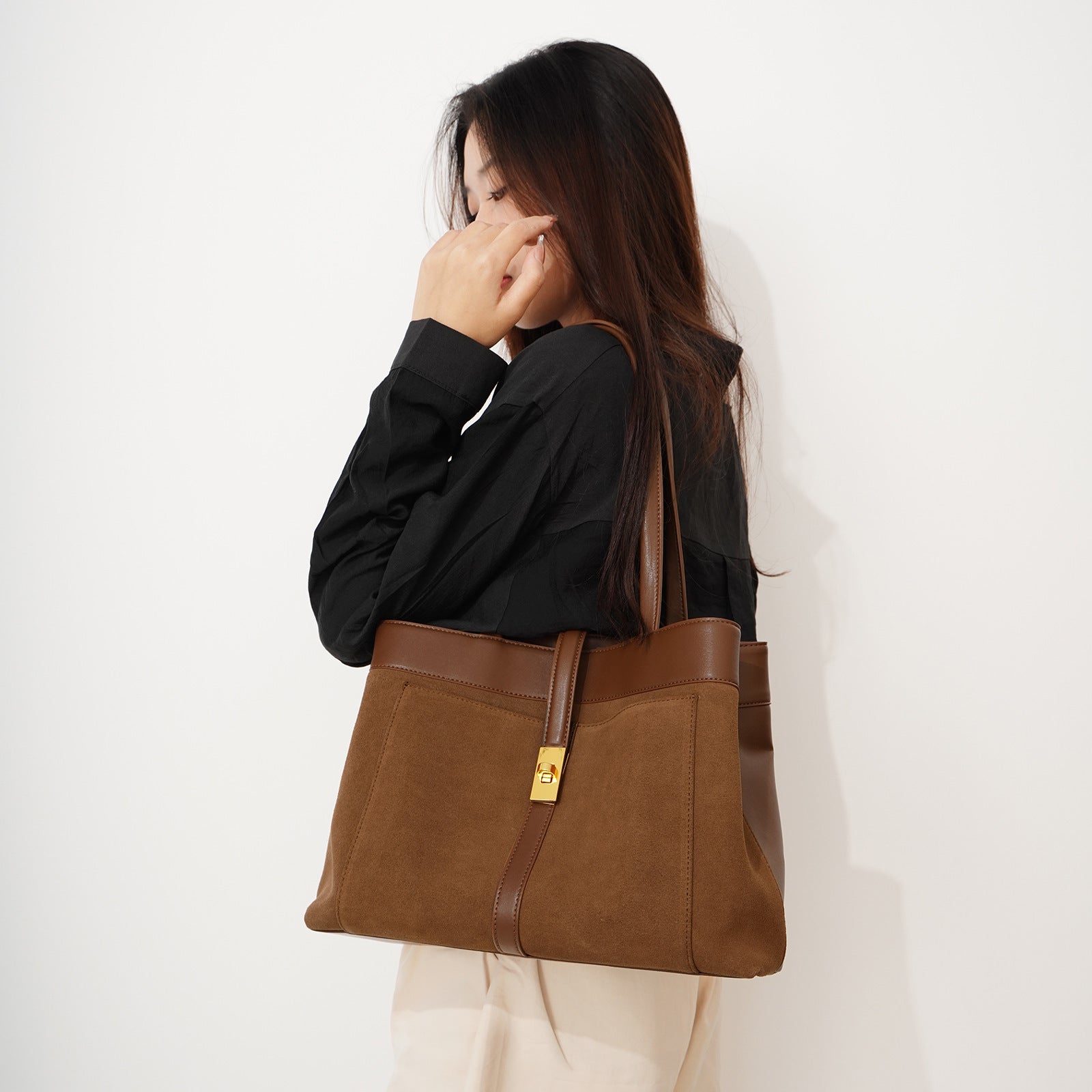 Woman holding a brown leather handbag against a white background