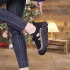 Person wearing black platform shoes with jeans in a blurred indoor setting