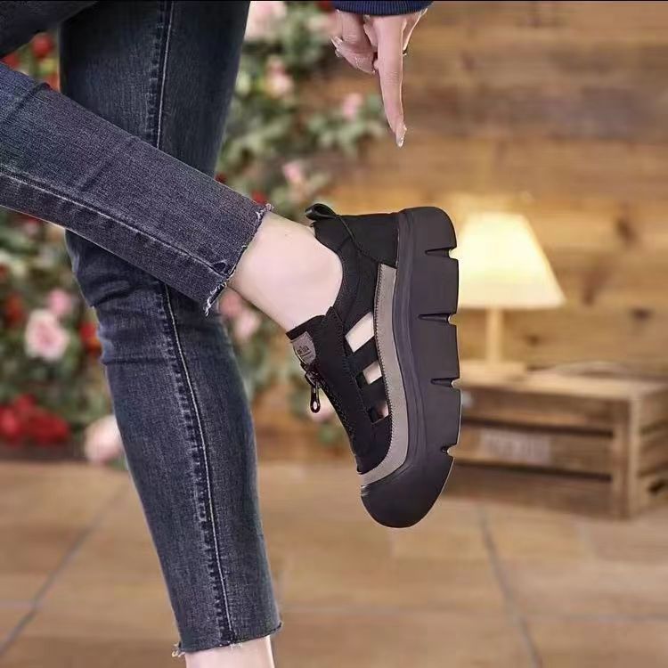 Person wearing black platform shoes with jeans in a blurred indoor setting