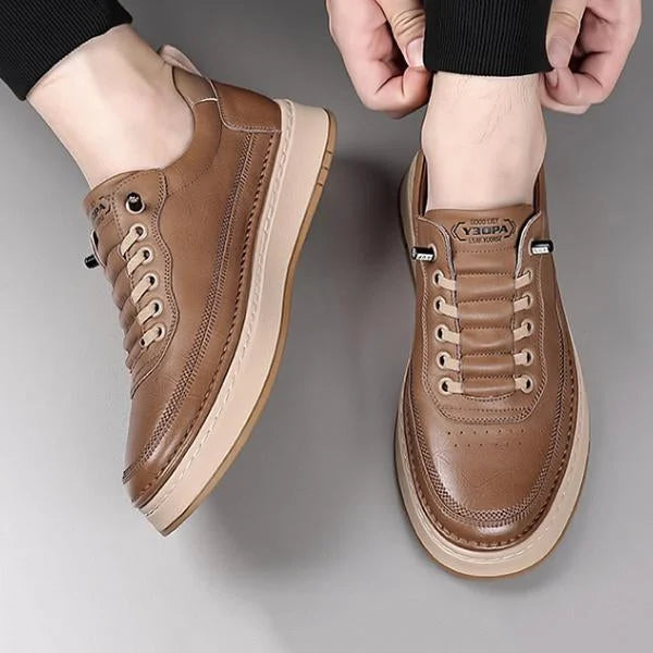 Brown leather shoes with beige soles worn by a person on a gray background