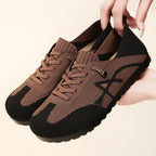 Brown and black sneakers held by a hand on a beige background